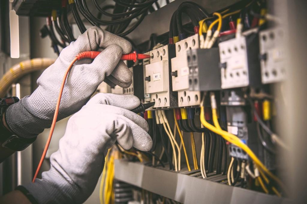 Électricité générale : électricien installant des câblages dans un tableau électrique